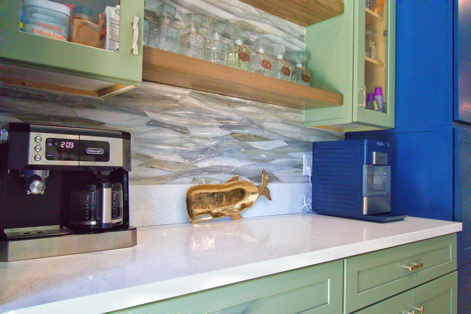 Bar counter in white speckled quartz with an espresso machine, a brass whale sculpture and a countertop ice maker