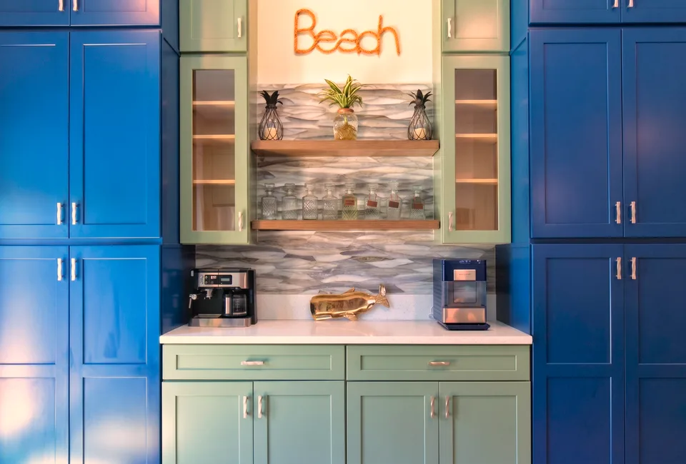 Beverage bar built into a navy pantry wall with a glass wave-tile backsplash