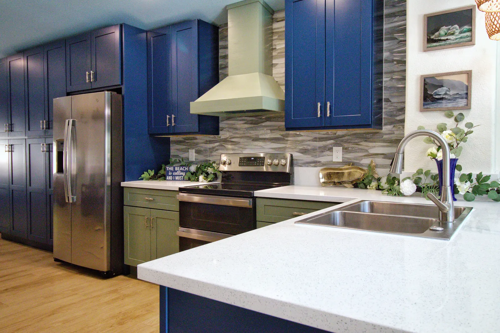 Kitchen corner with the sage range hood, glass wave backsplash and a stainless farmhouse sink in white speckled quartz