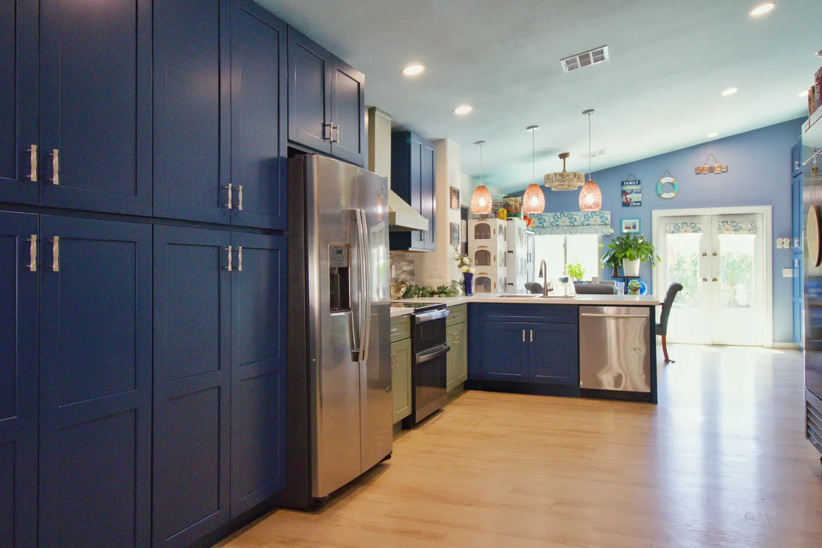 Wide view along the navy pantry wall through the kitchen to the dining area and its rattan pendant lights