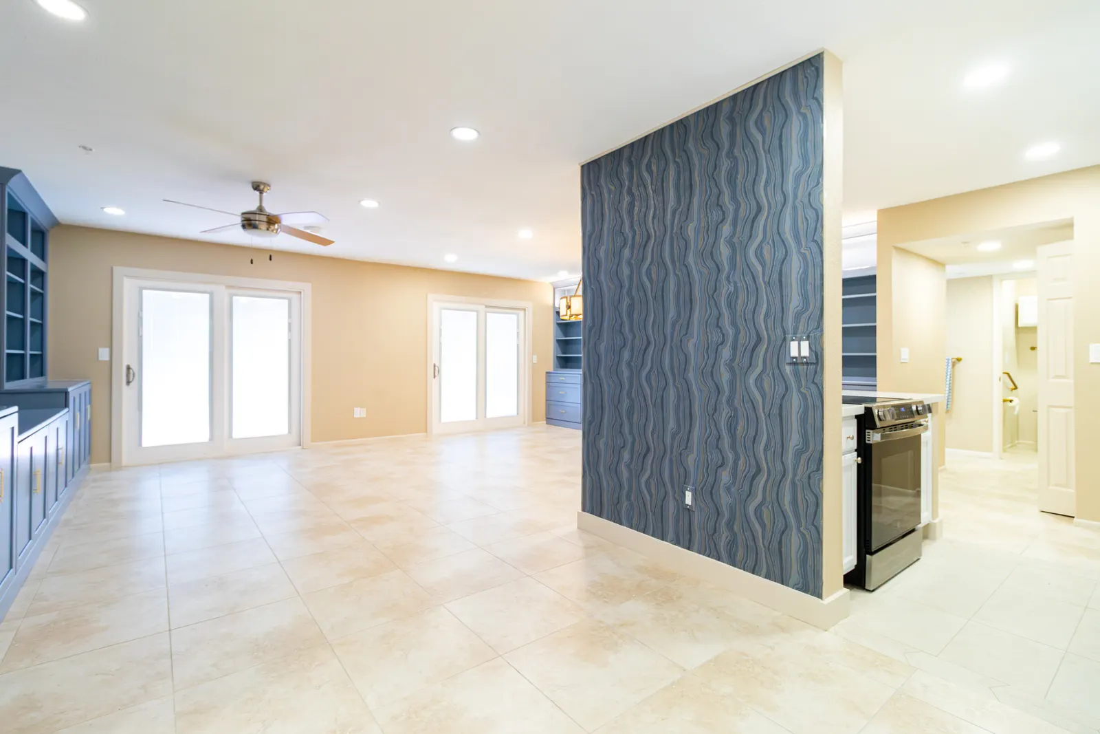 Great room with a blue wave-patterned accent wall dividing the living area from the kitchen range