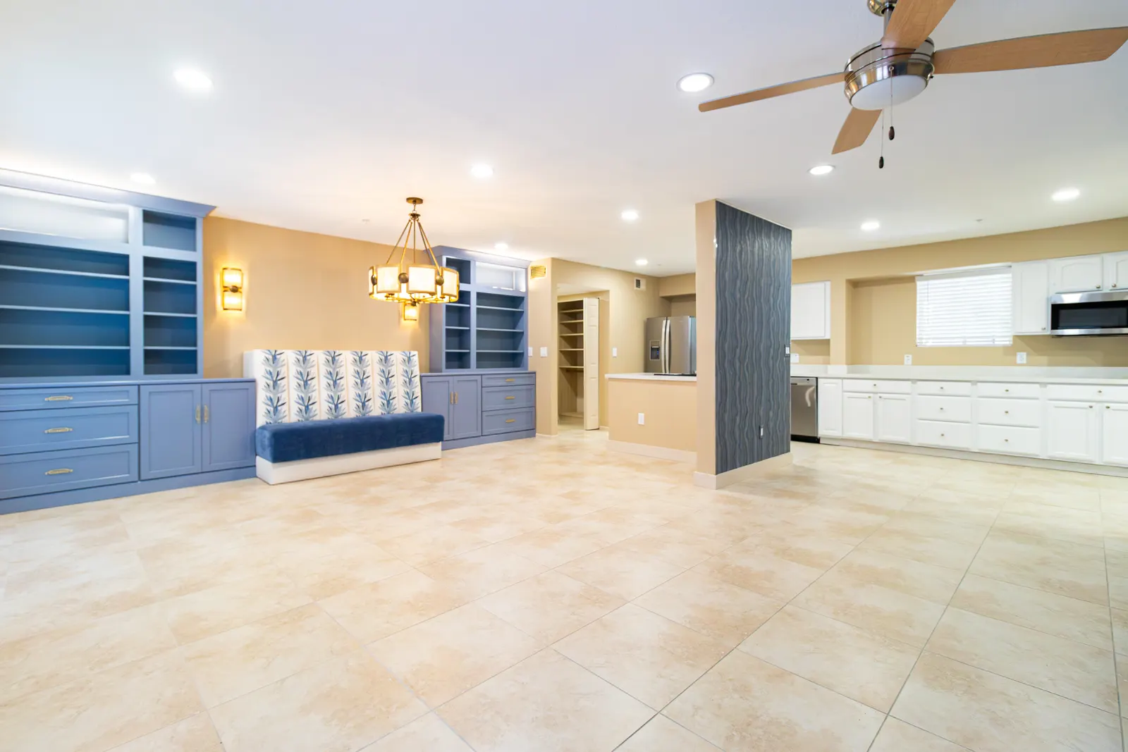 Open great room looking through to the white kitchen, with the blue banquette and built-ins along the left wall