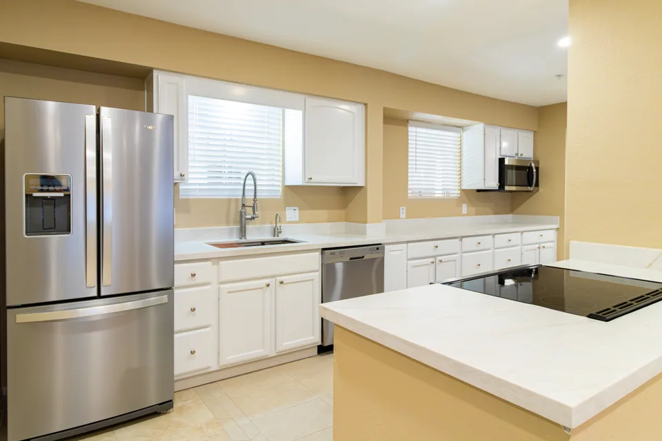 White shaker kitchen with quartz counters and an island cooktop
