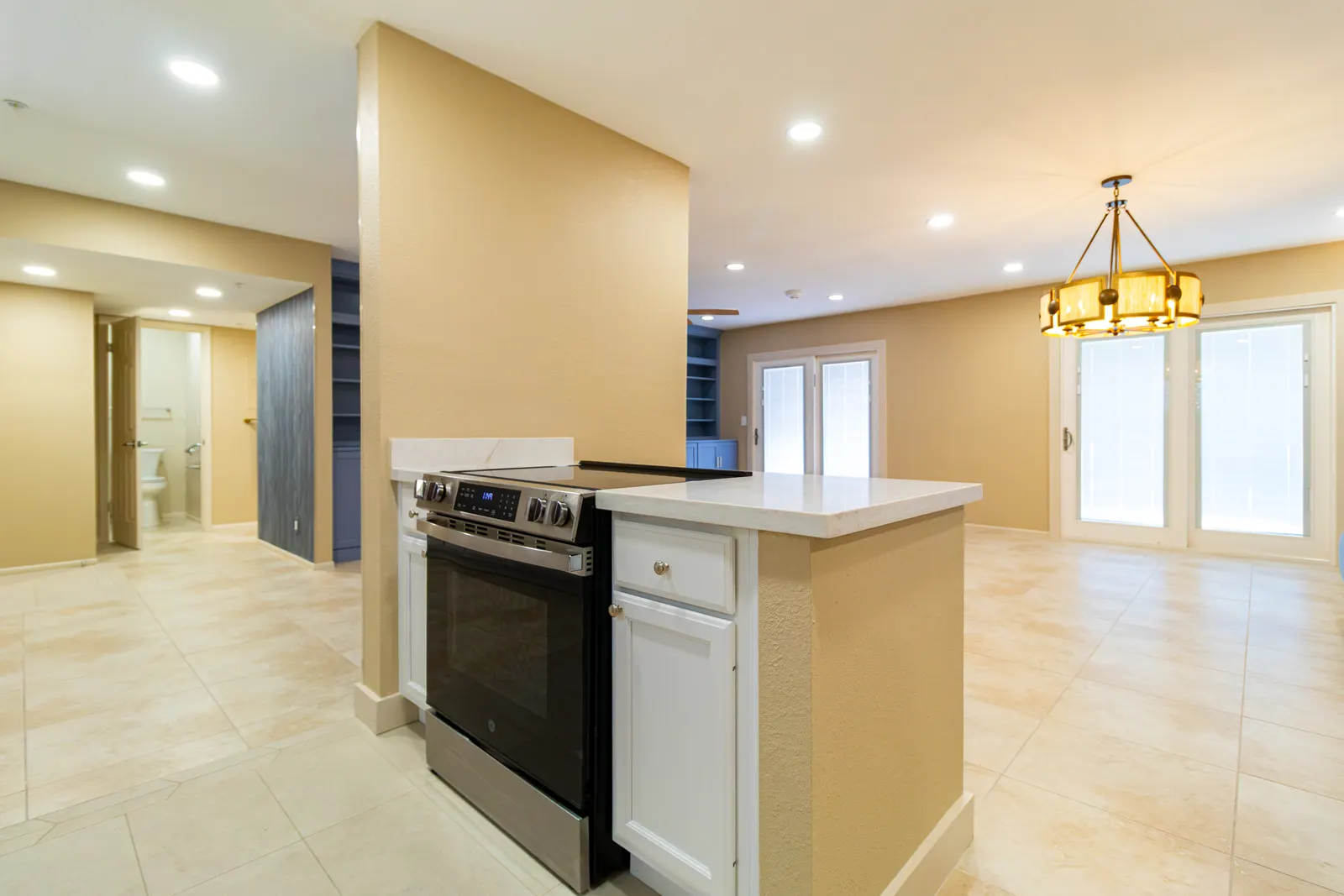 Kitchen island with a slide-in electric range, looking through to the great room and its brass chandelier