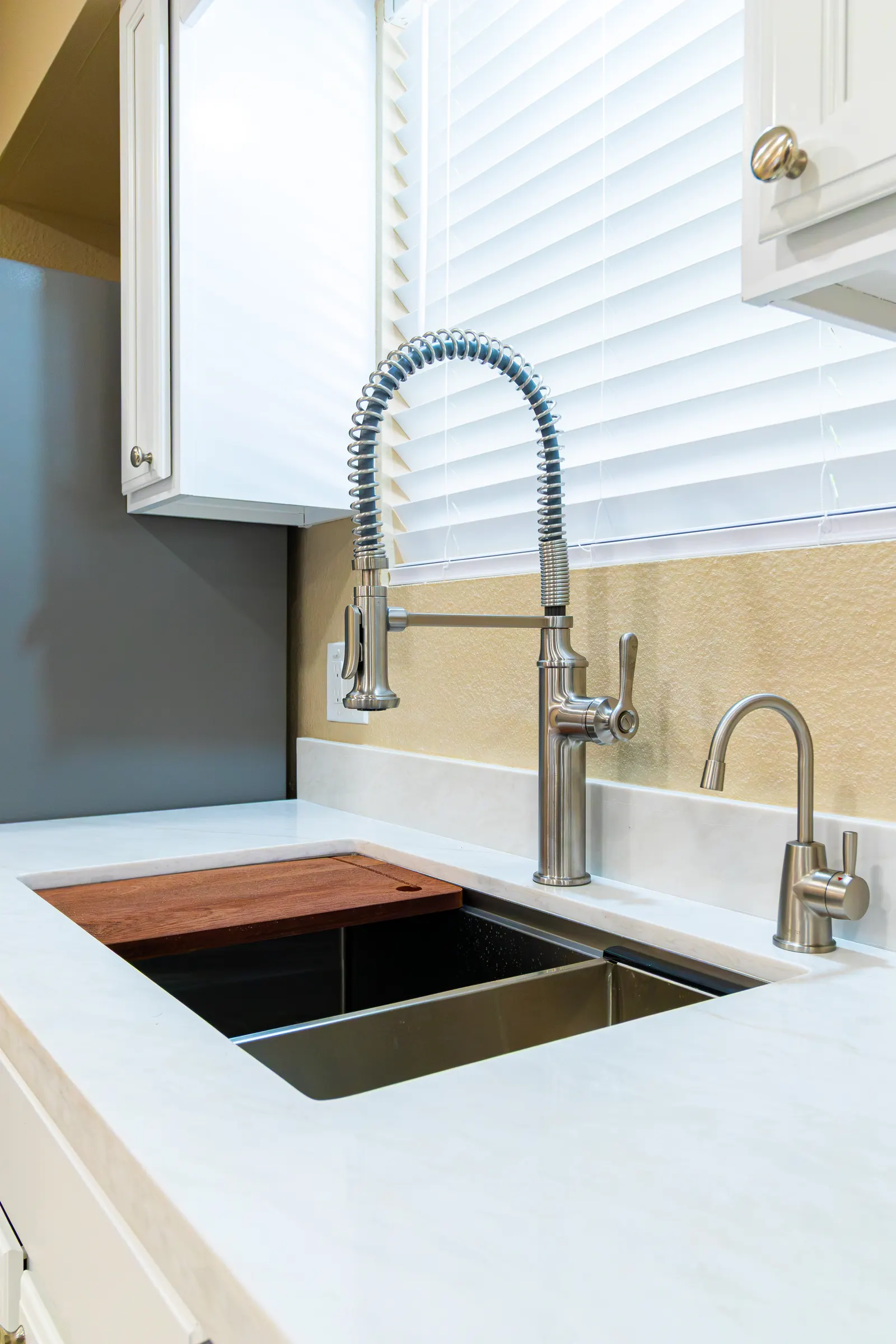 Undermount stainless sink with an integrated wood cutting board, spring-neck faucet and a separate filtered water tap